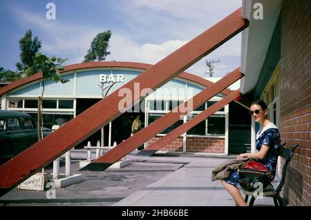 Femme assise à l'extérieur sur le banc café bar de la station-service près de Sao Paulo, Brésil, 1962 Banque D'Images