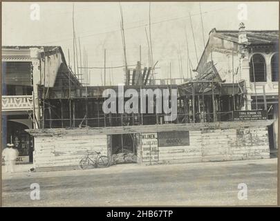 Chantier de construction, chantier de construction d'un immeuble situé dans un pâté de maisons d'une rue, probablement à Medan.Sur la clôture se trouve un signe de l'exécuteur : Firma Bennink Co. Architectes et entrepreneurs.Photo dans l'album photo de la société néerlandaise d'architecture et de sous-traitance Bennink et Riphagen à Medan dans les années ca.1914-1919., anonyme, Medan, 1914 - 1919, assistance photographique,imprimé gélatine argent, hauteur 147 mm × largeur 200 mm Banque D'Images