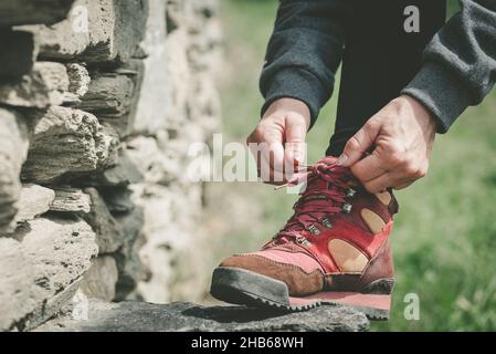 Mains de la femme laçage ses chaussures sur une pierre pendant une randonnée Banque D'Images