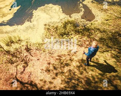 Vue de haut en bas femme senior stand tenant des bâtons nordiques et profiter de la vue panoramique sur le lac en belle journée ensoleillée.Texture et nature bien-être concept Banque D'Images