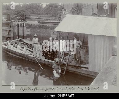 Overseer Nijssen fait de la plongée à Havelaarsluis (titre sur objet), Overseer Nijssen descend dans une combinaison de plongée d'un bateau de travail dans l'eau pendant les travaux sur le Havelaarsluis à Beekhuizen.Dans le bateau sont trois enfants européens.Partie de l'album photo souvenir de Voyage (partie 3), sur la vie de la famille Dooyer dans et autour de la plantation Ma Retraite au Suriname dans les années 1906-1913., Augusta Curiel, Suriname, 1900 - 1913, support photographique,hauteur 123 mm × largeur 169 mm Banque D'Images