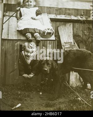 Garçon et fille frère et soeur jouant avec chien chenil dans le jardin C 1900-1910, Angleterre, Royaume-Uni Banque D'Images