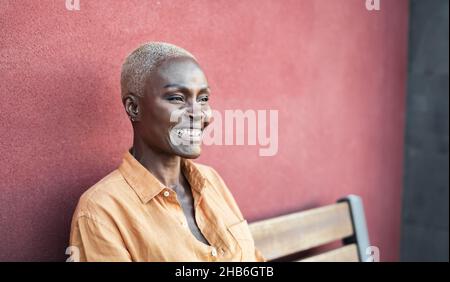 Portrait femme africaine senior souriant assis sur un banc à l'extérieur Banque D'Images