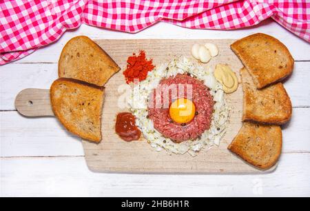 Vue de dessus de savoureux steak de bœuf cru tartare avec ail, jaune d'œuf, pain grillé, moutarde, ketchup,Poivrons et oignons - une variante typique de Czec Banque D'Images