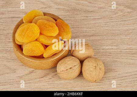 Abricots séchés dans une assiette en bois avec trois noix Banque D'Images