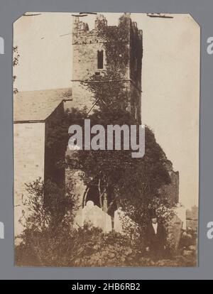 Vue sur la tour de l'église médiévale avec des remparts et une partie de l'église avec cimetière, vue sur la tour de l'église médiévale avec des remparts et une partie de l'église avec cimetière.Au premier plan un homme en costume avec chapeau de dessus, regardant dans la caméra., anonyme, c.1875 - c.1890, papier, imprimé albumine, hauteur 104 mm × largeur 76 mm Banque D'Images