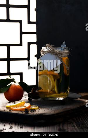 Théière avec thé aux agrumes chauds à base d'oranges, de citrons et de limes, boisson saine, fond rustique Banque D'Images