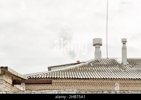 Cheminée grise sur un mur de briques avec un ciel nuageux d'hiver dans la ville Banque D'Images