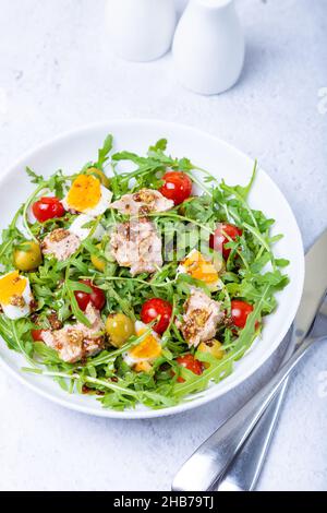 Salade de thon, d'arugula, de tomates, d'olives et d'œufs dans une assiette blanche. Un plat traditionnel. Gros plan. Banque D'Images