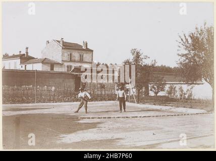 Deux joueurs de tennis sur un court de tennis clos, vraisemblablement en France, partie d'un album photo d'un photographe amateur français avec des photos de famille, distillerie Delizy & amp; Doistau fils, l'armée et les sites en France., anonyme, France, c.1900 - c.1910, papier, support photographique, hauteur 111 mm × largeur 160 mm Banque D'Images