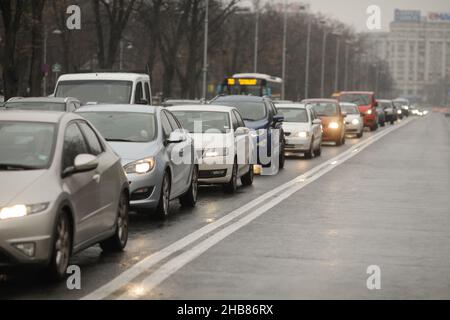Bucarest, Roumanie - 17 décembre 2021 : circulation de voitures dans une rue très fréquentée de Bucarest, par un hiver pluvieux. Banque D'Images