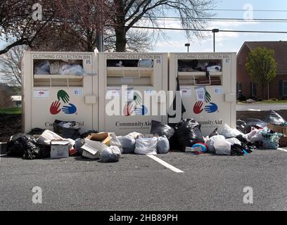 Bacs de dons de vêtements débordant avec plus de sacs sur le sol, dans un centre commercial local à Manheim, Pennsylvanie Banque D'Images