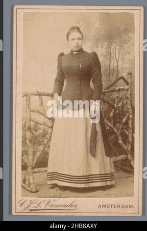 Portrait d'une femme inconnue, debout devant une clôture, Cornelis Johannes Lodewicus Vermeulen (mentionné sur l'objet), Amsterdam, 1888 - 1896, support photographique, carton,hauteur 103 mm × largeur 64 mm Banque D'Images