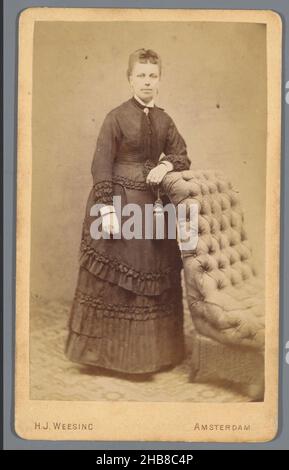 Portrait d'une femme inconnue près d'une chaise, Hermanus Jodocus Weesing (mentionné sur l'objet), Amsterdam, 1868 - 1900, carton, papier,imprimé albumine, hauteur 105 mm × largeur 64 mm Banque D'Images