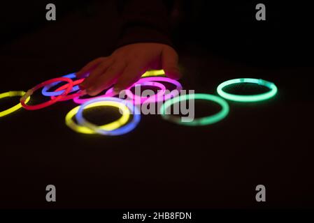 Des anneaux LED colorés illuminent le fond noir.Cercles lumineux en vert, rose, rouge, jaune, bleu.Fête paraphérnalia.Jouets pour enfants Banque D'Images