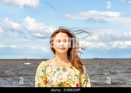 Un grand portrait d'une jeune femme avec des cheveux chancelants dans le vent sur le bord de mer. Banque D'Images