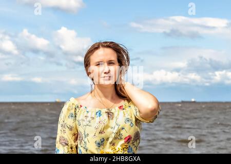 Un grand portrait d'une jeune femme avec des cheveux chancelants dans le vent sur le bord de mer. Banque D'Images