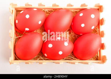 Œufs de Pâques décoratifs rouges dans une petite boîte en bois isolée sur une table blanche Banque D'Images