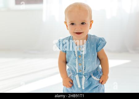 Très mignon et drôle bébé en denim sarafan faire les premiers pas.Petite fille souriante apprenant à marcher.Concept de la croissance des enfants et de l'enfance heureuse Banque D'Images