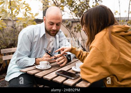 Deux jeunes regardent du contenu sur un smartphone assis à l'extérieur Banque D'Images
