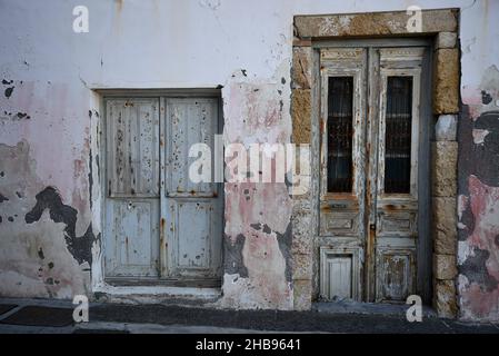 Ancienne façade de maison rurale abandonnée avec un mur en stuc et une porte et une fenêtre en bois gris à Koroni, Messinia Grèce. Banque D'Images
