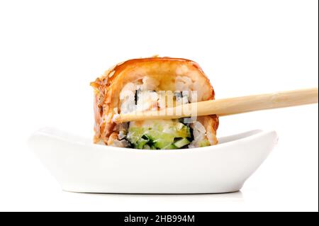 Petits pains à sushi au fromage à la crème, au nori et au concombre recouverts de sauce à l'anguille et au caramel dans des baguettes enrobées de sauce soja isolée Banque D'Images