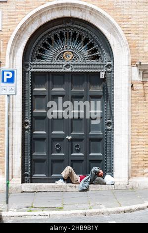 Un homme sans abri endormi s'est couché sur la vieille porte de Rome Banque D'Images