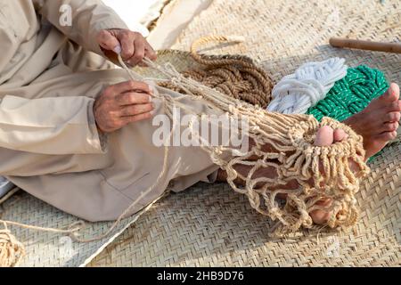 Le vieil homme triche le filet de pêche traditionnel, les mains dans le cadre Banque D'Images