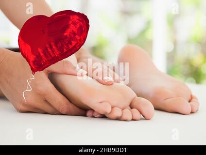 Image composite d'un ballon en forme de coeur rouge contre une femme recevant un massage des pieds Banque D'Images