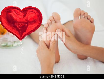 Image composite d'un ballon en forme de coeur rouge contre une femme recevant un massage des pieds Banque D'Images