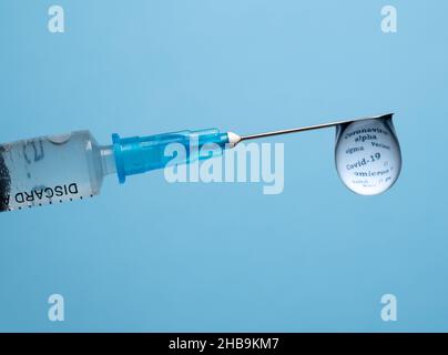Concept d'efficacité des vaccins contre le covid-19 avec une goutte à l'extrémité de la seringue hypodermique reflétant les mots décrivant le coronavirus Banque D'Images