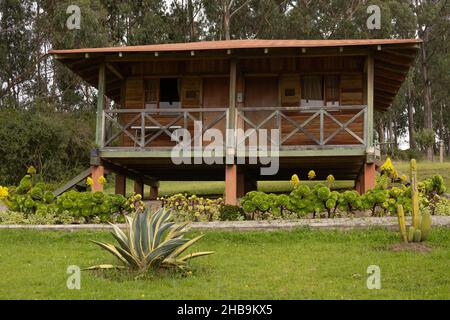 façade en bois d'une cabine avec balcon, style rustique avec jardin et herbe autour, arrière-plan avec arbres dans la journée, campagne détendue Banque D'Images