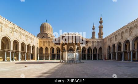 Fontaine d'ablution servant de support à la cour de la mosquée historique publique du Sultan al Muayyad, avec arrière-plan de couloirs voûtés entourant la cour, le dôme et les minarets de la mosquée, le Caire, Egypte Banque D'Images