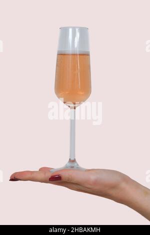 Une femme avec de beaux ongles rouges tenant un verre de champagne sur un fond blanc Banque D'Images