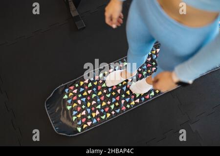 Points d'acupuncture de la stimulation du pied.Femme debout sur un tapis orthopédique de massage des pieds.Tapis de massage aux pierres colorées Banque D'Images
