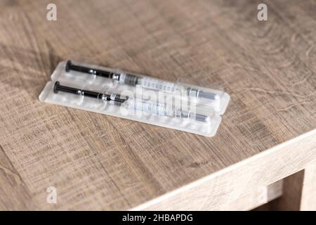 Un emballage contenant deux seringues sur une table en bois.Les injections de drogue sont faites d'un tube en verre avec des marques de volume sur lui et le nee Banque D'Images
