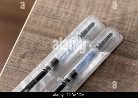 Un portrait d'un paquet contenant deux seringues sur une table en bois.Les doses de médicament sont faites d'un tube en verre avec des marques de volume sur lui et le Banque D'Images