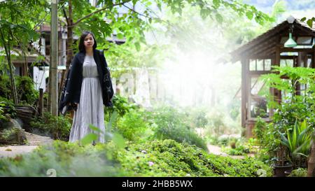 Femme asiatique se réjouissent de marcher et de prendre des photos dans un parc naturel, elle regarde l'appareil photo et sourit. Banque D'Images