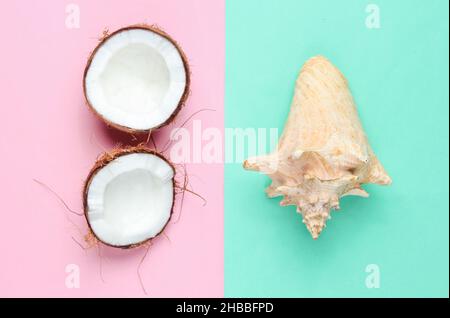 Deux moitiés de noix de coco hachée et de seashell sur fond bleu rose pastel Banque D'Images