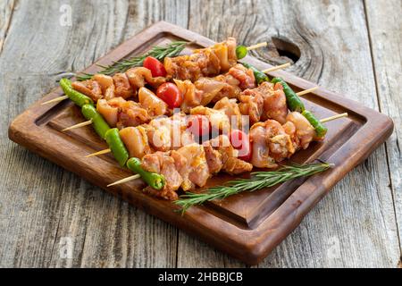 Brochettes de poulet sur fond en bois.Gros plan de brochettes de poulet crues marinées dans la sauce tomate.Vue horizontale Banque D'Images