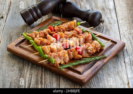 Brochettes de poulet sur fond en bois.Gros plan de brochettes de poulet crues marinées dans la sauce tomate.Vue horizontale Banque D'Images