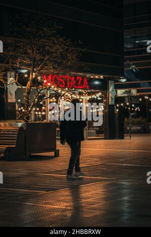 BUENOS AIRES, ARGENTINE - 23 septembre 2021: Une photo verticale d'un homme marchant près de Mostaza à Puerto Madero, Buenos Aires, Argentine la nuit Banque D'Images