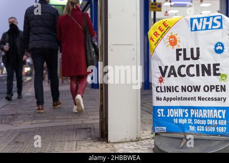 Les acheteurs de Noël marchent au-delà de l'affiche vaccin contre la grippe offrant gratuitement la grippe jab aux personnes admissibles à la pharmacie Sidcup Londres Angleterre Banque D'Images