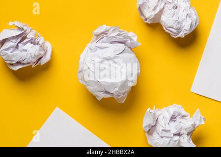 Boules de papier froissé et feuilles blanches de papier sous forme de triangles, avec espace pour le texte.Arrière-plan jaune.Copier l'espace. Banque D'Images