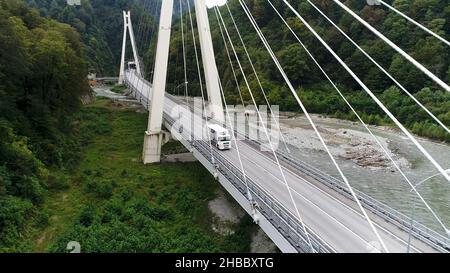 Vue aérienne d'un nouveau pont en béton avec autoroute et conduite de camion blanc, transport de marchandises concept.Camion blanc se déplaçant le long de la forêt verte, vue Banque D'Images