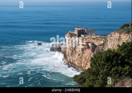Phare de Nazaré, Portugal par une journée ensoleillée avec des vagues s'écrasant sur la falaise Banque D'Images