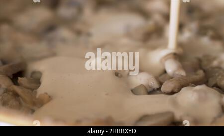 Gros plan de la poêle avec les champignons dans une sauce à la crème.La crème épaisse est versée dans la poêle avec des champagnes frits, préparation de sauce aux champignons. Banque D'Images