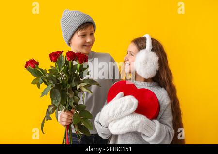 Enfants heureux avec cadeau et fleurs sur fond de couleur.Célébration de la Saint-Valentin Banque D'Images