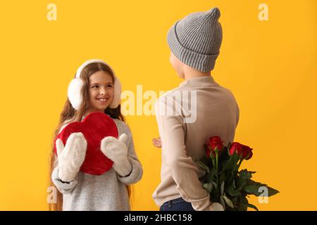 Enfants heureux avec cadeau et fleurs sur fond de couleur.Célébration de la Saint-Valentin Banque D'Images