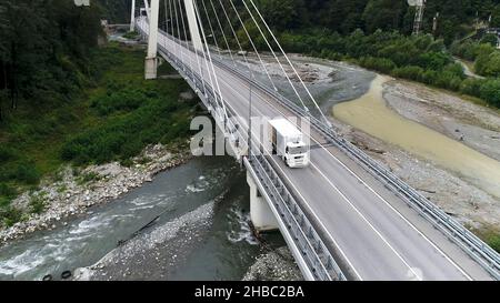 Vue aérienne d'un nouveau pont en béton avec autoroute et conduite de camion blanc, transport de marchandises concept.Camion blanc se déplaçant le long de la forêt verte, vue Banque D'Images